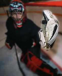 Young goalie in net with glove extended