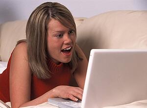 Girl laying on sofa with laptop computer