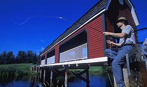 man sitting on bridge fishing