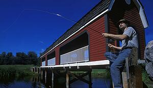 man sitting on bridge fishing