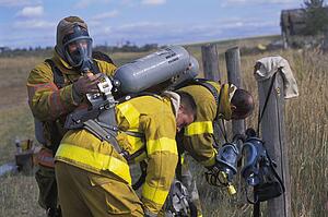Fireman adjusting equipment on partner
