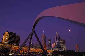 Curved span of bridge with city skyline in background