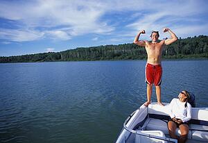 Man standing on rear of boat while flexing muscles