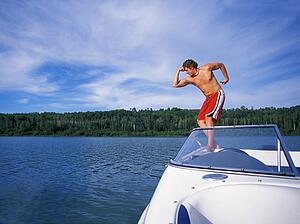 Man standing on rear of boat while flexing muscles