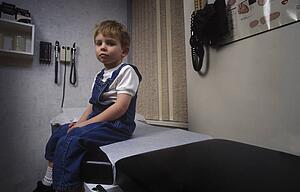 Boy sitting on table in doctor's office