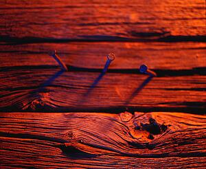 Three nails in wood in red tones
