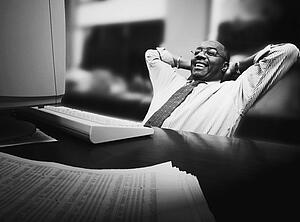 Man leaning back in chair in front of desk with computer