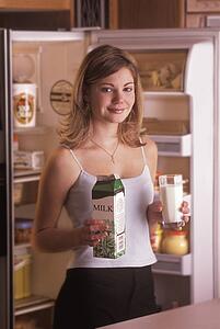 Girl getting glass of milk from fridge