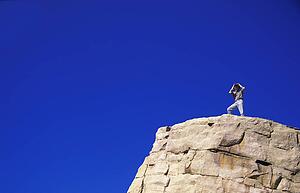Hiker with binoculars on cliff edge