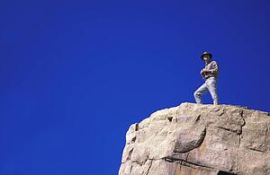 Hiker with binoculars on cliff edge