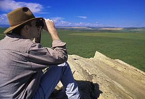 Hiker with binoculars on cliff edge