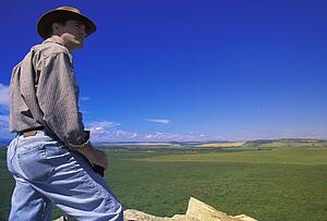 Hiker with binoculars on cliff edge