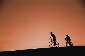 Silhouette of cyclists on hill