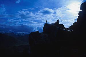 Hiker standing on large rock at edge of cliff