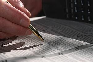 Closeup of man's hand circling Investment in newspaper