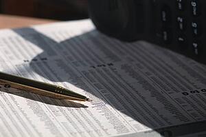 Closeup of pen and circled Investment in newspaper