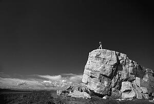 Hiker on top of large boulder in black and white