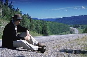 Hiker sitting on edge of country road