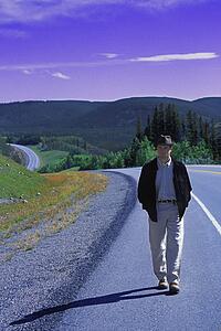 Hiker walking on edge of highway