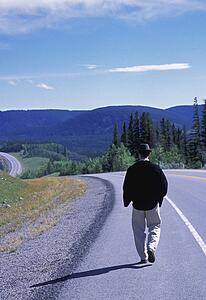 Hiker walking on edge of highway