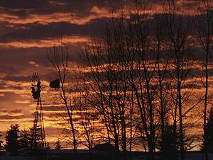 Sunset at farm with wind driven pump