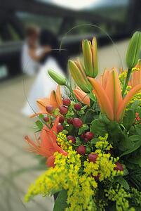 Bouquet of flowers with bride and groom kissing in the background