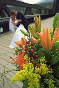 Bouquet of flowers with bride and groom kissing in the background