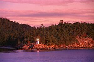 Small lighthouse with trees and hill behind