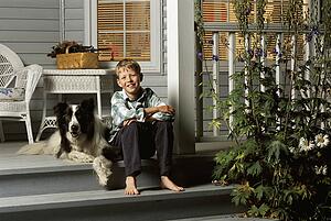 Boy sitting with dog on porch steps