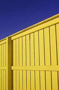 Bright yellow wood fence with deep blue sky