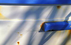 Hull of blue and white boat with corrosion marks