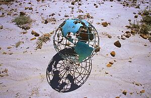 Wire globe outside on sand