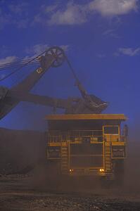 Large ore truck getting filled with drag line bucket