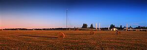 Bales of hay in field with pumping station in background