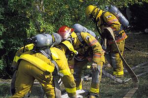 Firemen outside picking up fire hose