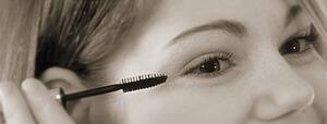 Young woman putting on mascara