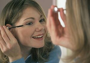 Young woman putting on mascara