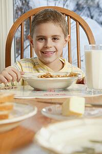 Young boy eating cereal at breakfast table