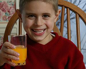 Young boy smiling and holding orange juice