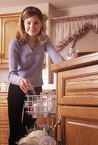 Teenager loading dishes into dishwasher