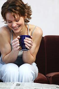 Woman drinking coffee and reading newspaper