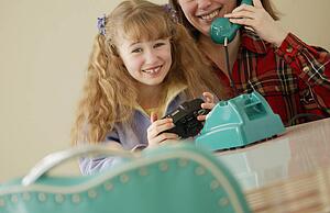 Child holds camera while mother on phone