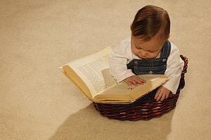 Baby reading a book in a basket