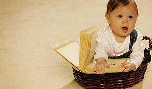 Baby reading a book in a basket