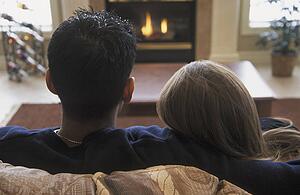 Couple snuggles by fireplace