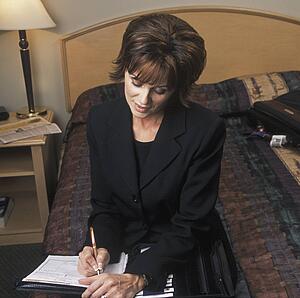 Businesswoman fills out forms in hotel bedroom
