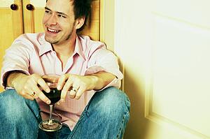 Man smiles while holding wine