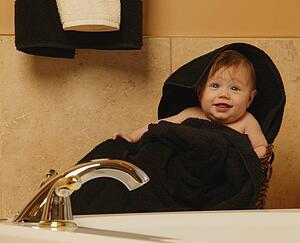 Baby wrapped in towel in bathroom