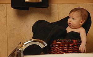Baby sits in bathroom basket