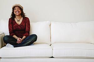 Laughing woman sits on sofa